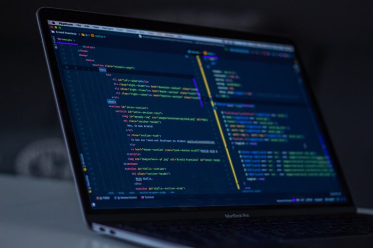 Developer writing code on a laptop with editors and syntax highlighting representing UI/UX design process